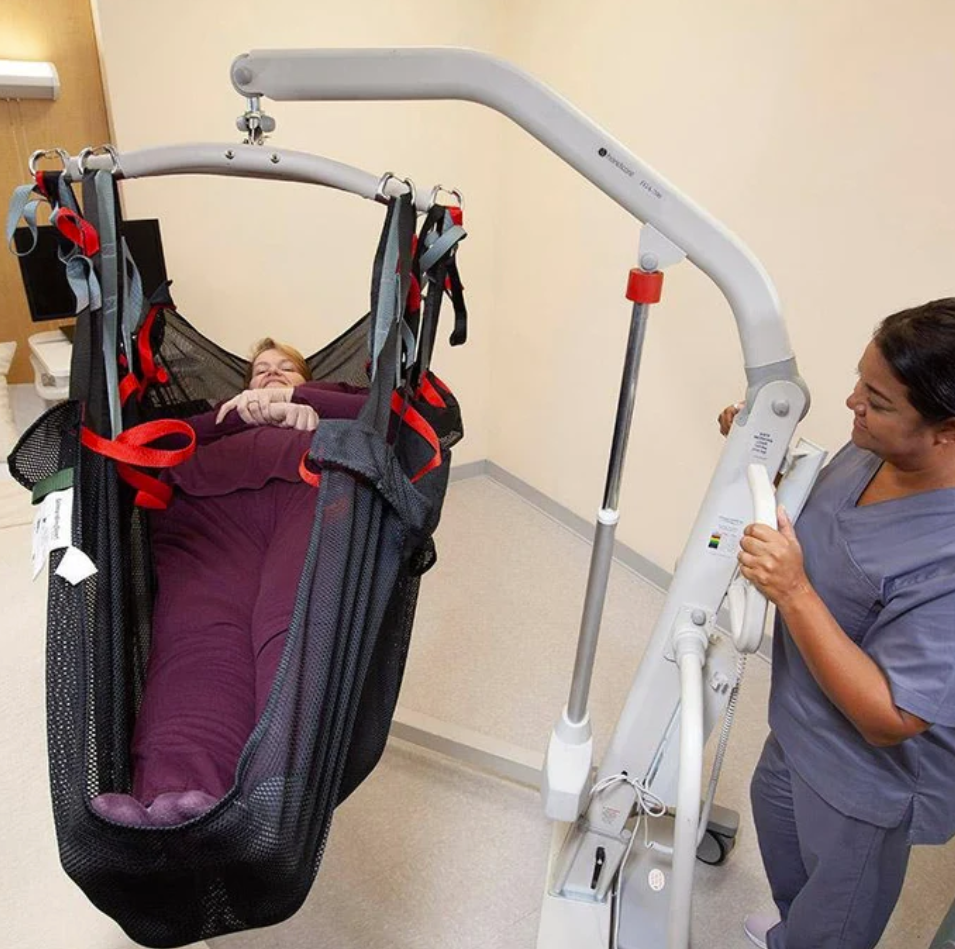 Caregiver next to patient using floor patient lift