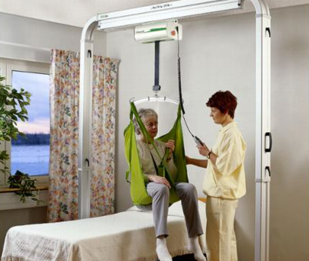 Woman using ceiling patient lift beside caregiver